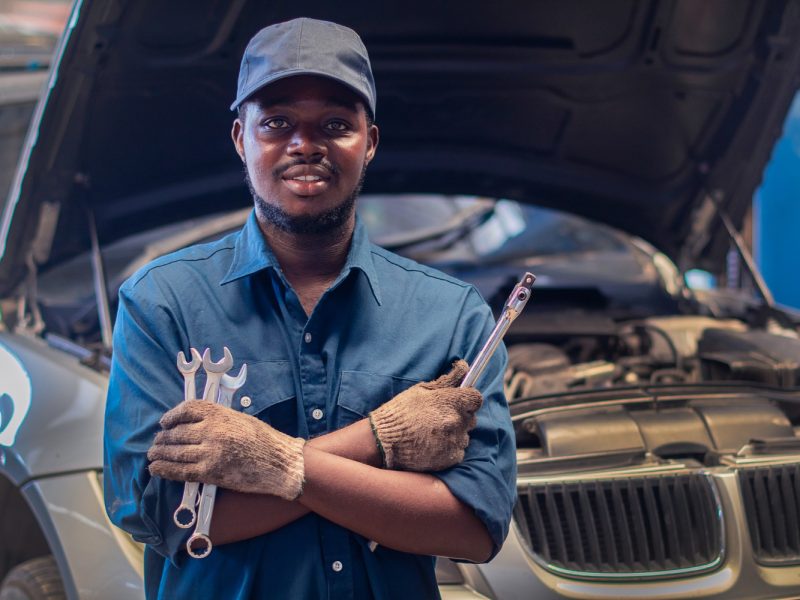 african-man-mechanic-uniform-with-crossed-arms-wrenches-standing-car-repair-station