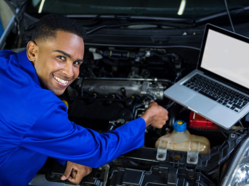 mechanic-examining-car-engine-with-help-laptop