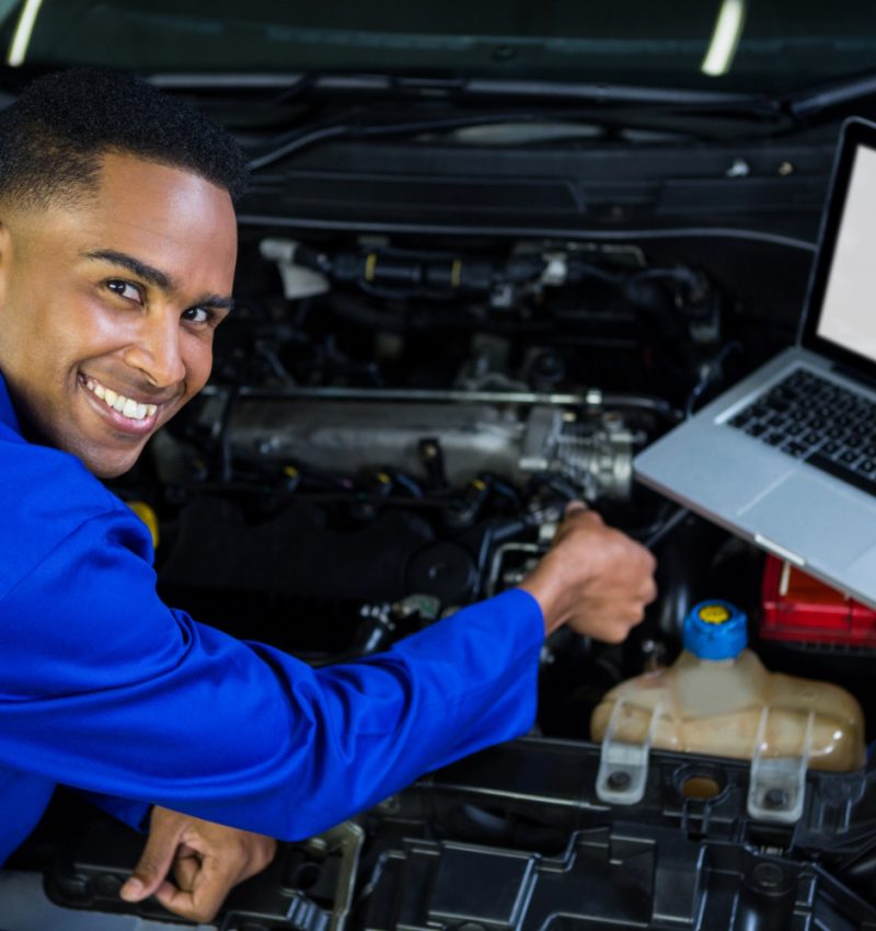 mechanic-examining-car-engine-with-help-laptop